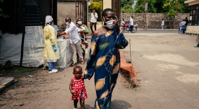 A woman wearing a mask as a preventive measure enters Kyeshero Hospital after passing a checkpoint for hand washing and health screening in Goma
