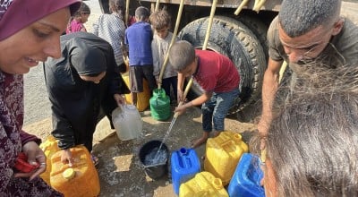 People gather to fill containers with clean water from a tank.