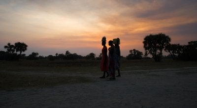 Women crossing in Leer County, Unity State, South Sudan at sunset. Deep in the swamps, the island has become a haven for thousands of people fleeing conflict. Photo: Kieran McConville/Concern Worldwide