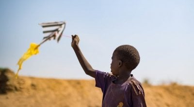 A young boy flies a home made kite on the streets of Juba's PoC in South Sudan. Photo: Steve De Neef / Concern Worldwide.