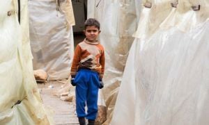 A young Syrian refugee stands between the tents at an informal settlement in the north of Lebanon. Photo: Dalia Khamissy / Concern Worldwide. 