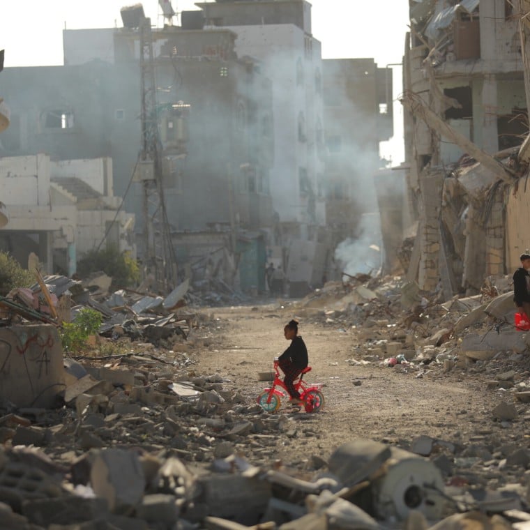 Child on tricycle cycles through destroyed buildings in Gaza