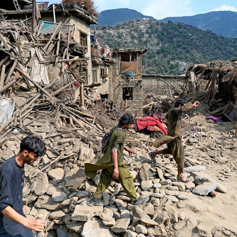 Afghans walk past houses damaged by earthquakes in Kunar province, in Eastern Afghanistan, on September 1, 2025